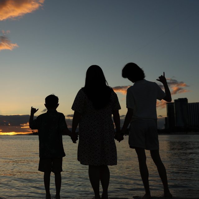 Jessy and her two boys holding hands on the beach at sunset